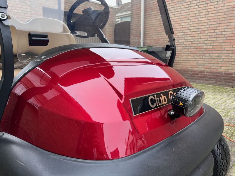 Detail van een rode Club Car-golfkar met werklamp