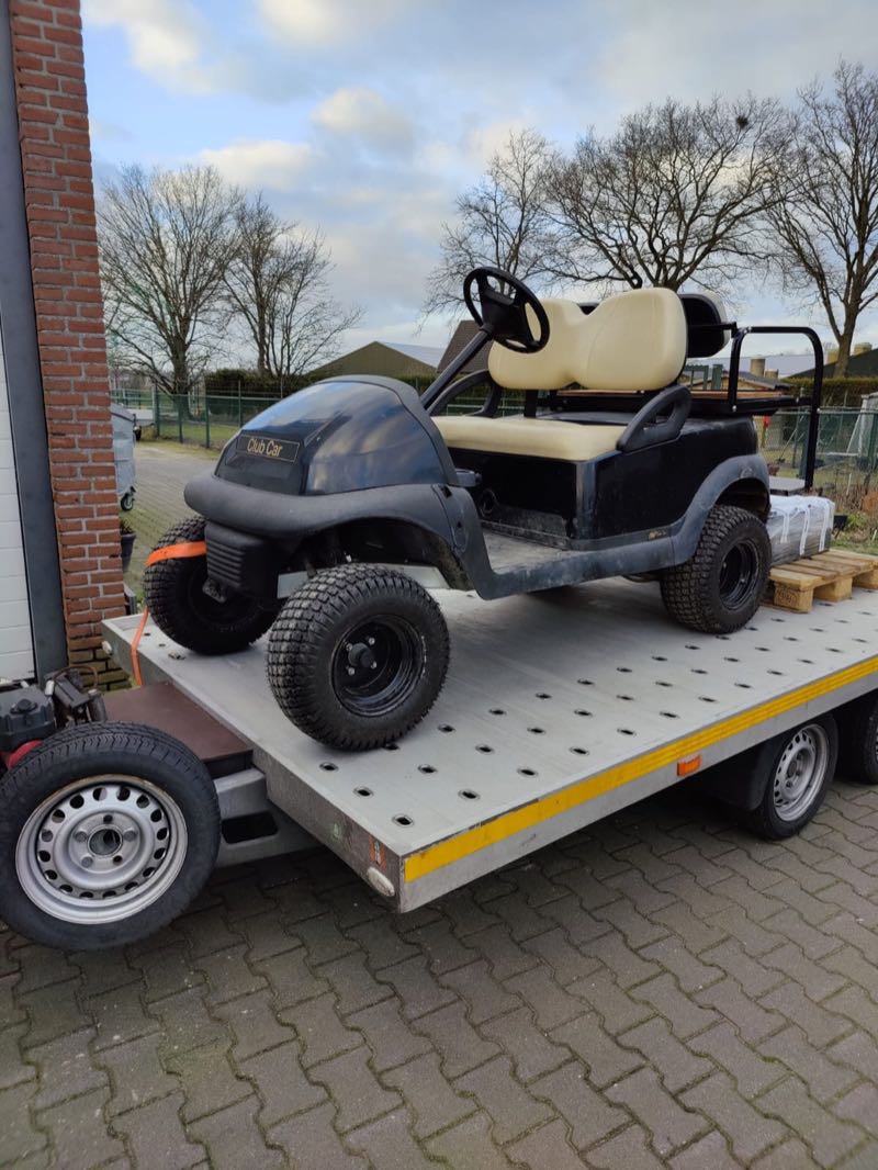 Golfkar met terreinbanden op een aanhanger, klaar voor levering